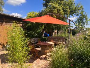 an orange umbrella in a garden with a table and chairs at Hof Appelbue - Urlaub in zwei Ferienwohnungen im Storchendorf Bergenhusen in Bergenhusen