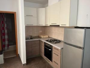 eine Küche mit weißen Schränken, einem Herd und einem Kühlschrank in der Unterkunft Apartments Sun Rogoznica in Podglavica