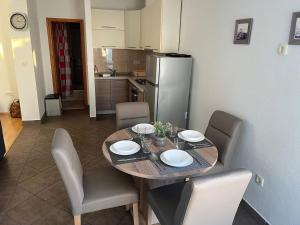 ein Esstisch mit Stühlen und eine Küche in der Unterkunft Apartments Sun Rogoznica in Podglavica