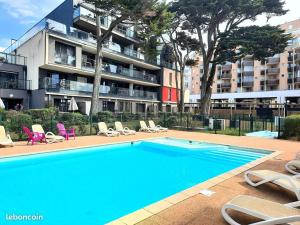 a swimming pool with chairs and a building at Le Dream by Tranquil at Home - Parking, Piscine, Plage et Wifi in Pornichet