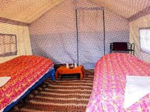 a room with two beds and a table in it at Tsomoriri Inn Cottages in Karzok Gömpa