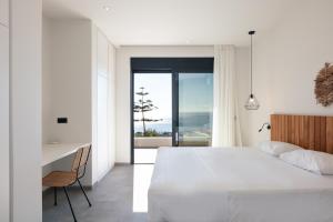 Un dormitorio con una cama blanca y un escritorio y una ventana. en Villa Hestia, en Rethymno 64 fotos más