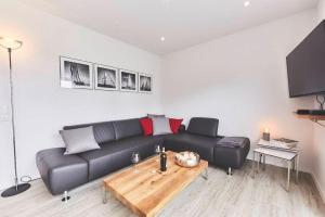 a living room with a black leather couch and a table at Treibgut in Norddeich