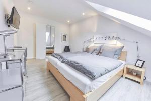 a white bedroom with a bed and a staircase at Treibgut in Norddeich
