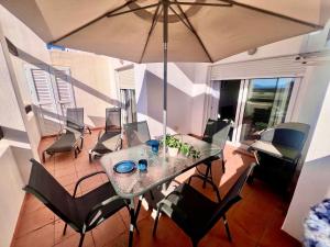 a table with chairs and an umbrella in a room at Condado de Alhama PENTHOUSE SV11 in Alhama de Murcia