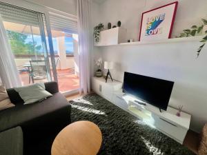 a living room with a couch and a flat screen tv at Condado de Alhama PENTHOUSE SV11 in Alhama de Murcia