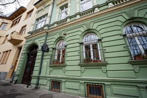 a green building with three windows on a street at Victoria Apartment 1901-Apartament ultracentral Oradea ,lângă Piața Unirii in Oradea