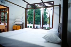 een slaapkamer met een bed met een groot raam bij Maradana Rest in Mirissa