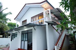 een wit huis met een balkon en een trap bij Maradana Rest in Mirissa