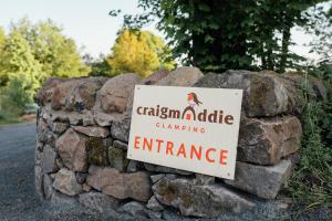a stone wall with a sign on it at Glamping Pods in Milngavie