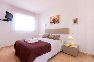 a white bedroom with a large bed and a television at MALDIVAS I Apartment in La Pineda +35 photos