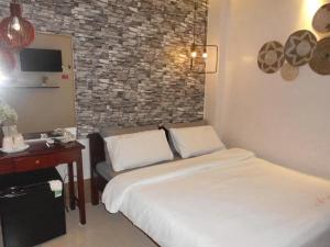 Un dormitorio con una cama y un escritorio y una pared de ladrillos. en MOTEL Thanh Hằng, en Can Tho