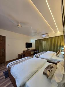a hotel room with three beds and a television at Hotel Fortune in Ayodhya