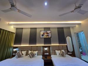 a hotel room with two beds and a mirror at Hotel Fortune in Ayodhya