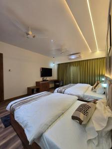 a hotel room with three beds and a television at Hotel Fortune in Ayodhya