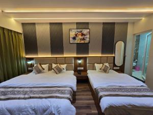 a hotel room with two beds and a mirror at Hotel Fortune in Ayodhya