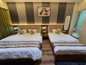 a hotel room with two beds and a mirror at Hotel Fortune in Ayodhya