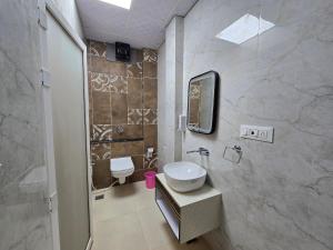 a bathroom with a sink and a toilet and a mirror at Hotel Fortune in Ayodhya