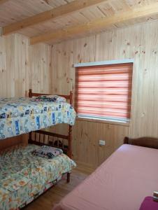 two beds in a wooden room with a window at Cabaña el descanso in Pelluhue