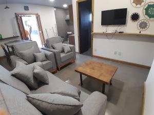 a living room with couches and a table and a tv at Casa nova a 2 min do mar in Arroio do Sal