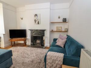 a living room with a blue couch and a fireplace at Princess Beach House in Swanage