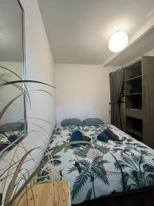 a bedroom with a bed with palm trees on it at Le petit refuge 28m2 2 personnes avec extérieur in Denain