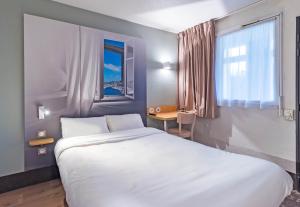 a bedroom with a large white bed and a window at B&B HOTEL Saint-Brieuc in Tregueux +34 photos