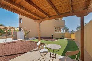 a patio with a table and chairs and a green lawn at Sandra La Perla in El Médano