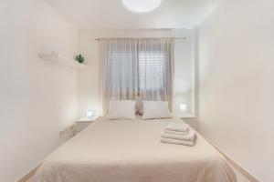 a white bedroom with a large bed with towels on it at Sandra La Perla in El Médano +21 photos