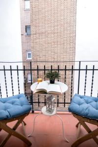 una mesa con un libro en un balcón con 2 sillas en 8Rooms Madrid, en Madrid