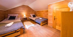 Dos camas en una habitación con paredes de madera. en Agroturystyka Folwarczek Pokoje i Apartamenty, en Ustroń