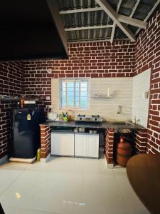 a large kitchen with a brick wall at Nature's Nest Cottages in Kundakal