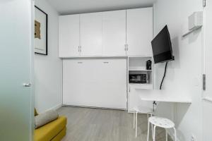 a kitchen with white cabinets and a table and a tv at Sol Apartment III - En el centro de Madrid in Madrid