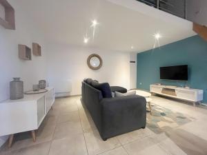 a living room with a couch and a tv at A deux pas des péniches in Castelsarrasin