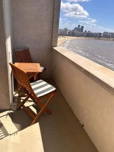 two chairs and a table on a balcony with the beach at Rambla Montevideo in Montevideo