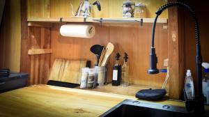 a kitchen counter with a sink and a shelf with utensils at The Cabin in Hakuba +22 photos