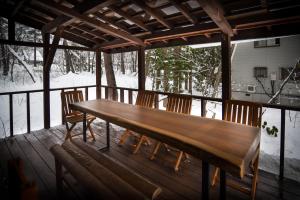 a wooden bench sitting on a porch with two chairs at The Cabin in Hakuba