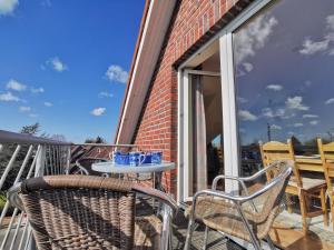 Un patio con dos sillas y una mesa en un balcón. en Wohnung 07, en Horumersiel