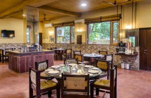 un ristorante con tavoli e sedie in una stanza di Rega Tuskar's Riverside Resort Jim Corbett a Ramnagar