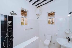 a white bathroom with a toilet and a sink at Bwejuu Beach Duplex Bungalow in Bwejuu