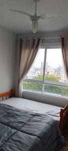 une chambre avec un lit et une grande fenêtre dans l'établissement Apto em Torres próximo a praia, à Torres