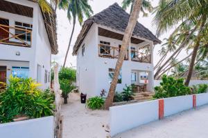 a house on the beach with palm trees at Bwejuu Beach Duplex Bungalow in Bwejuu