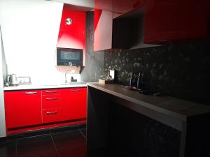 a red kitchen with red cabinets and a counter at Apartament Grey in Tuchola