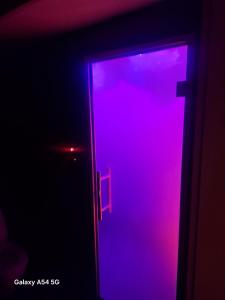 an open door with purple light in a dark room at Apartament Grey in Tuchola