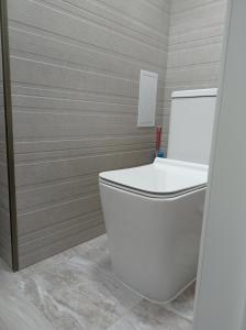 Un baño con un inodoro blanco en una habitación. en Тихий Замок, en Bishkek