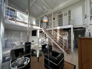 a living room with a staircase and chairs at La Maison de Jane Château&Beauval in Cormeray