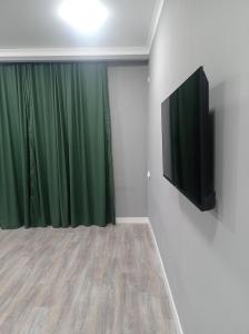 Habitación con cortina verde y TV de pantalla plana. en Тихий Замок, en Bishkek