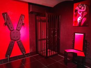 a room with a red room with a cage and a chair at Apartament Grey in Tuchola