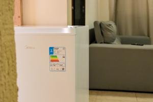 ein weißer Kühlschrank in einem Raum mit einem Stuhl in der Unterkunft Pousada kanoas suites in São José da Coroa Grande