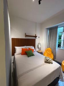 a bedroom with a large white bed with orange and green pillows at Studio Moderno in Botafogo in Rio de Janeiro